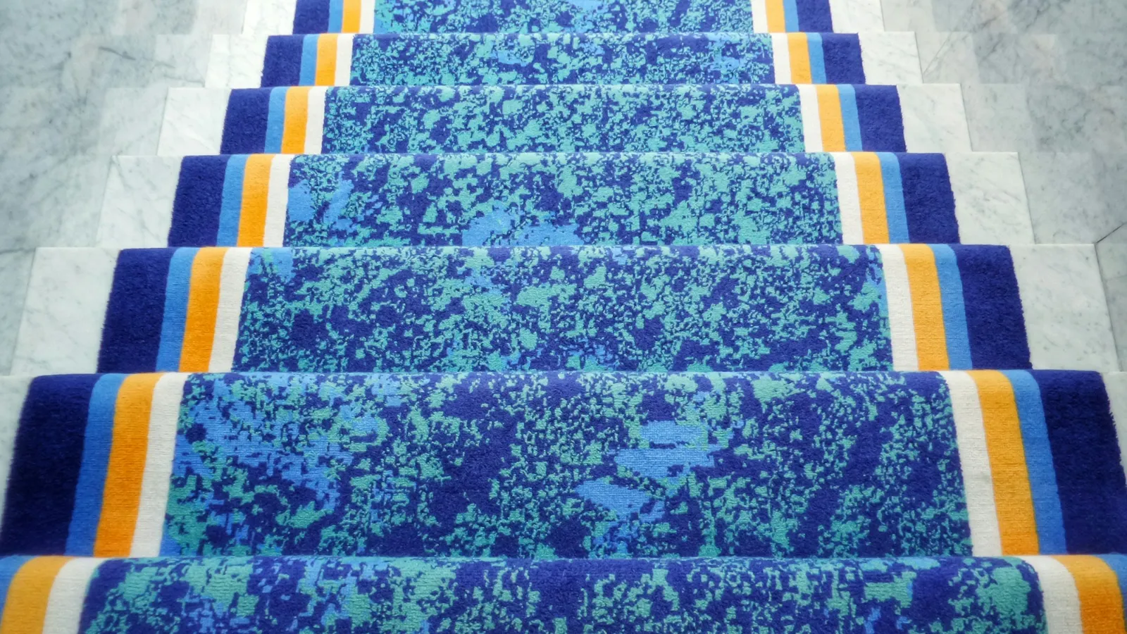 Blue mottled carpet covering a long flight of stairs