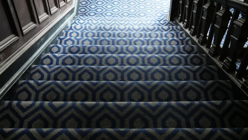 Blue patterned carpet fitted up a flight of stairs