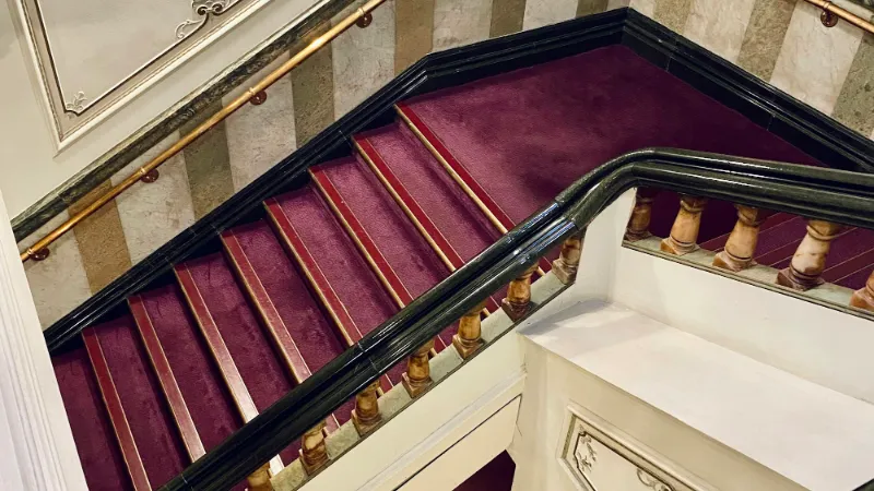 Burgundy carpet on a grand staircase with a curved handrail