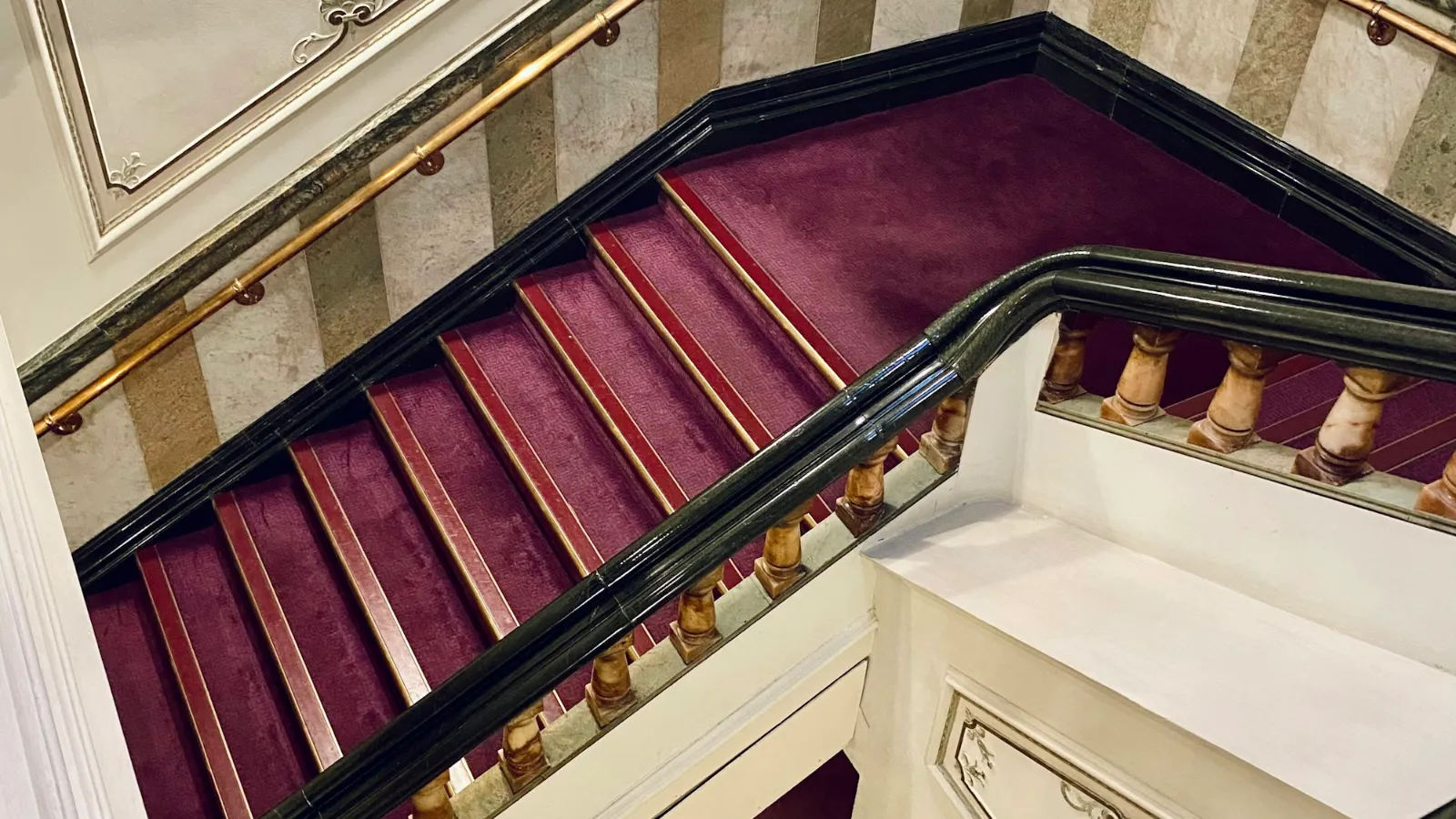Burgundy carpet on a grand staircase with a curved handrail