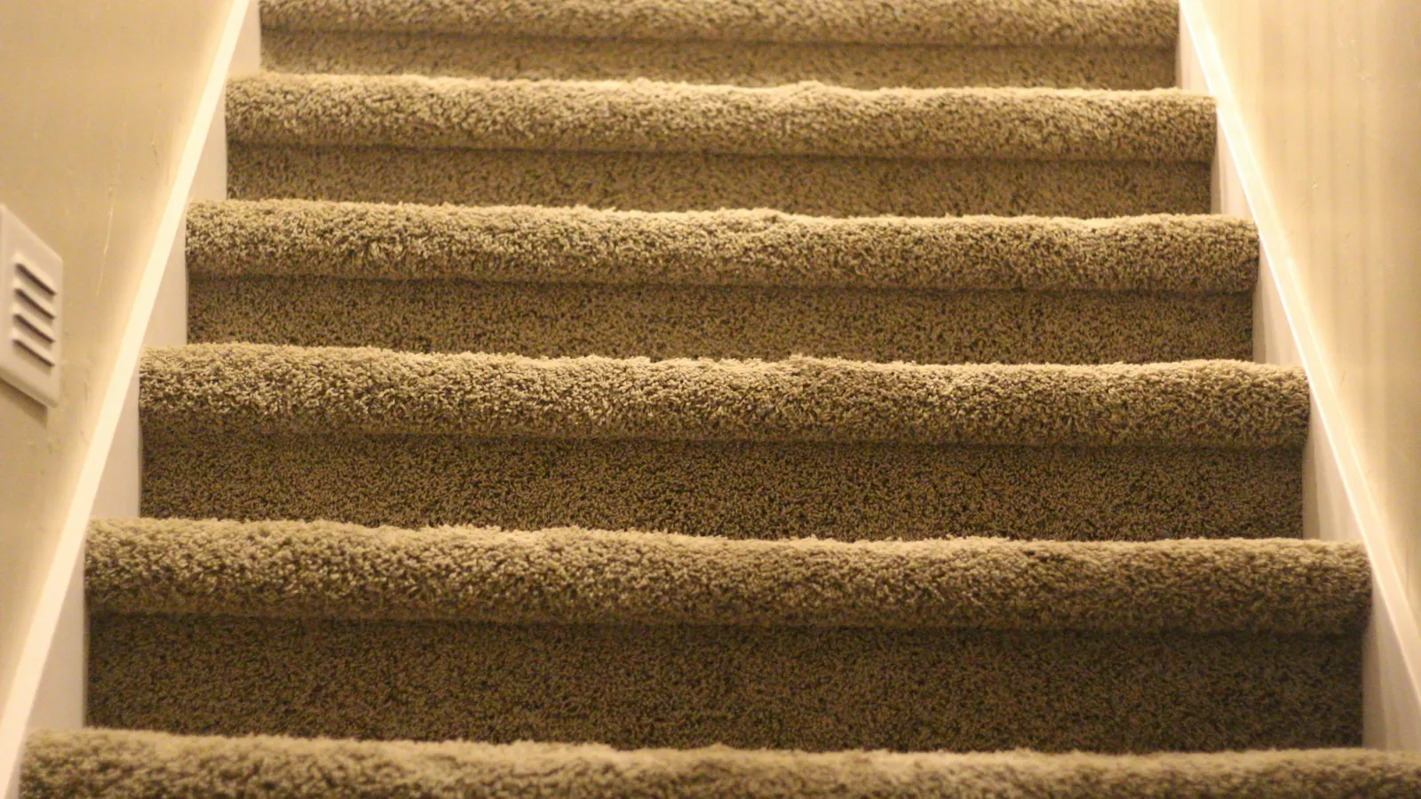 Close view of beige carpeted steps and their nosings