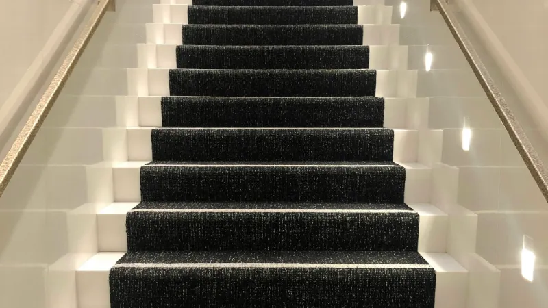 Dark carpeted staircase with a deep pile on every tread