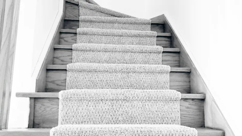 Light grey carpeted stairs in a bright, minimal stairwell