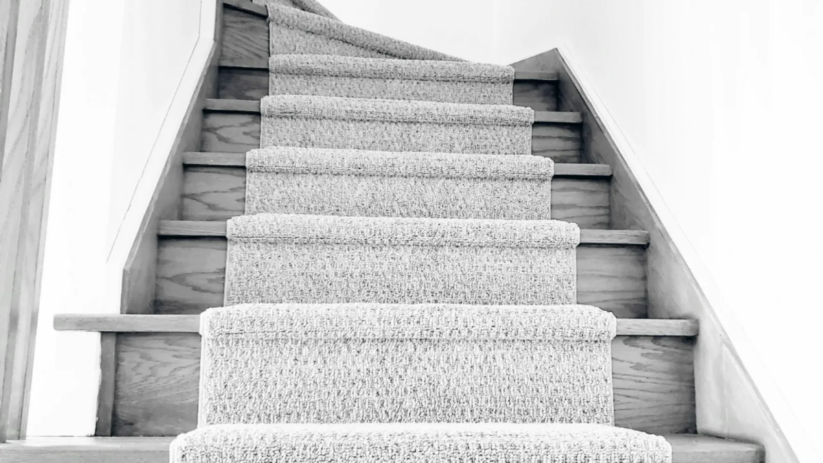 Light grey carpeted stairs in a bright, minimal stairwell