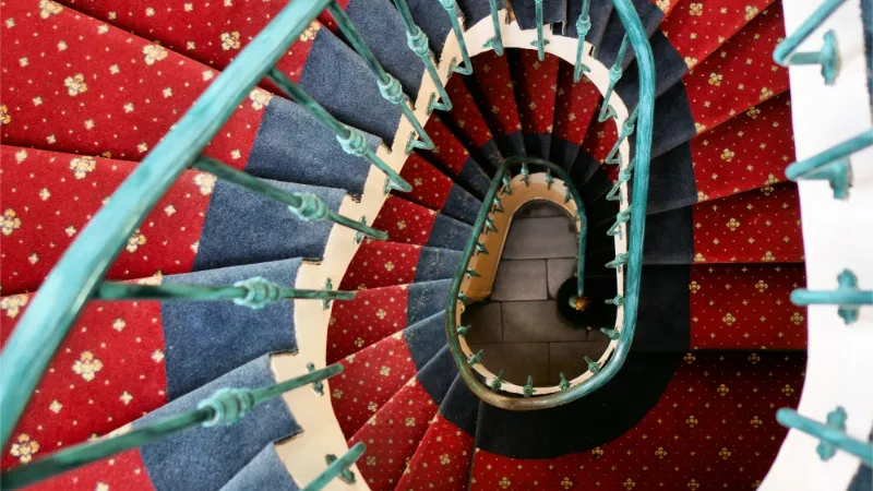 Looking down a spiral staircase with a patterned runner