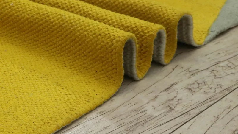 Mustard wool textile folded on a timber floor