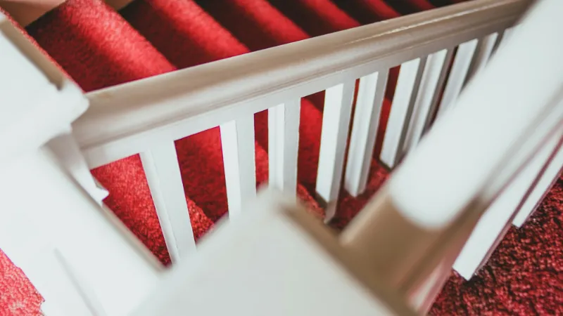 Red carpet on stairs beside white-painted balusters
