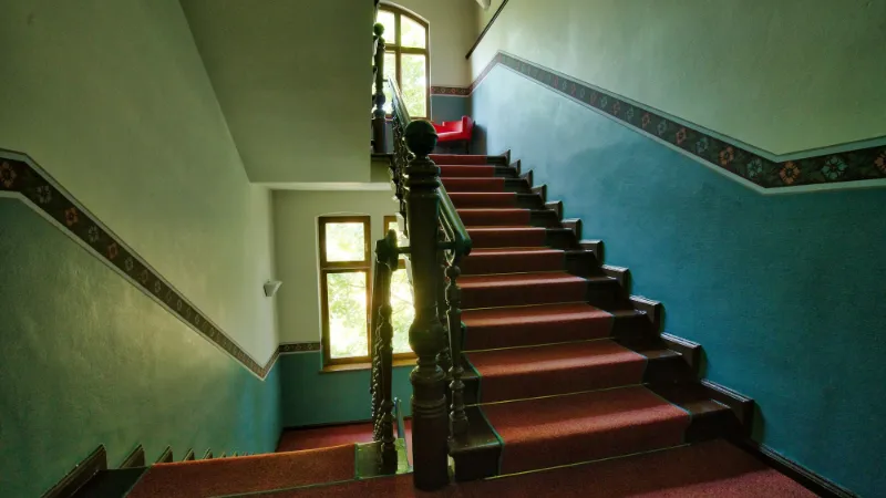 Red runner on a hallway staircase with painted walls