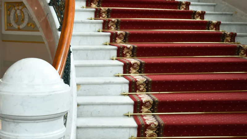 Red runner with a border on white-painted stairs