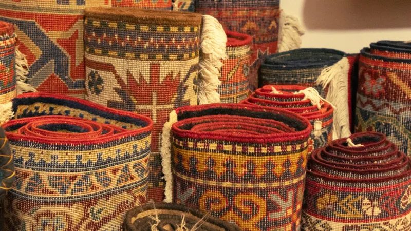 Stacked woven rugs at a market