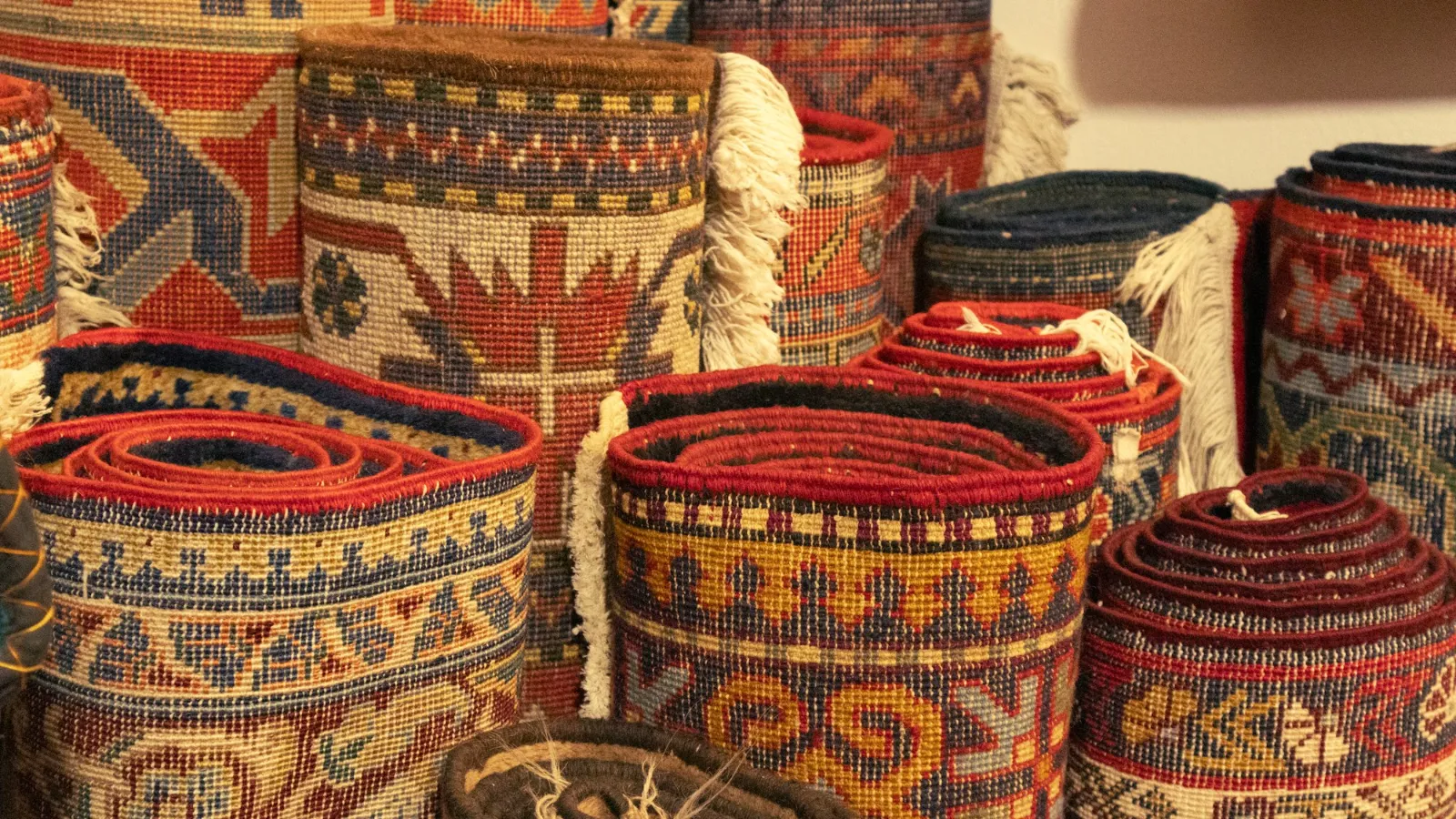 Stacked woven rugs at a market