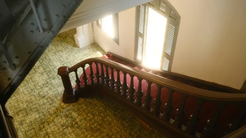 Turning staircase with a carved timber banister and green carpet