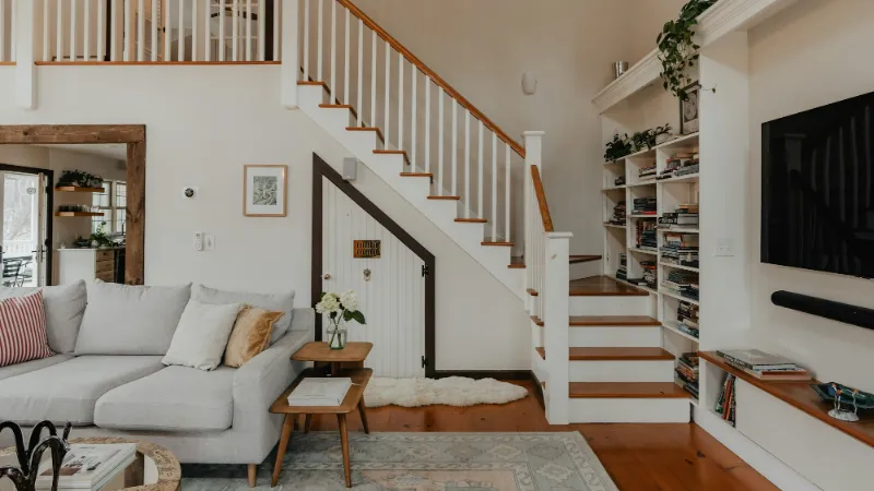 White staircase with dark timber treads beside a living area